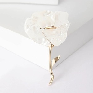 Elegante rozenbroche met witte harsblaadjes en gouden bladeren op witte houder