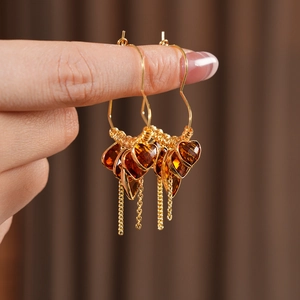 Detailed macro of 18K gold plated heart earring with amber glass and tassel fringe