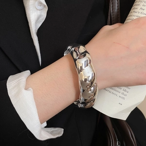 Macro detail of silver polished twisted rope bangle on wrist with elegant high-gloss finish