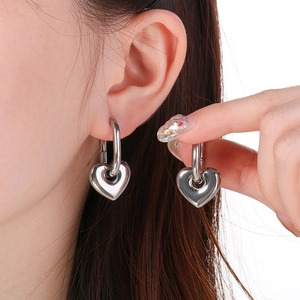 Gros plan détaillé d'une boucle d'oreille cœur en argent portée par un mannequin pour le style