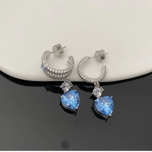 Détail de boucles d'oreilles argentées serties pavé avec pendentif cœur bleu élégant