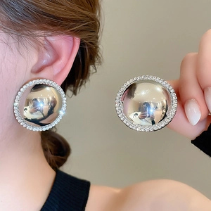 Detail of silver round stud earrings featuring a polished mirror surface and pavé rhinestones