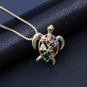 Detailed macro shot of golden sea turtle pendant with colorful gemstones on black leather