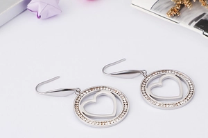 Detail of silver heart-shaped drop earrings with pavé zircons in a circular frame