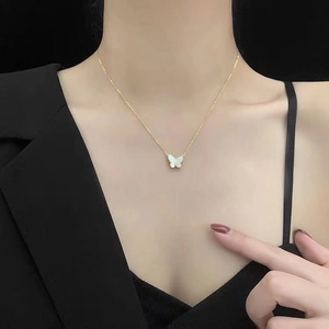 Détail d'un collier en titane doré avec un pendentif papillon en nacre blanche élégant