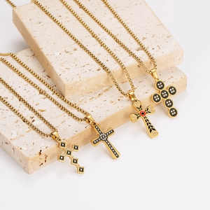 Gold stainless steel cross pendant necklaces with crystals on a beige stone display