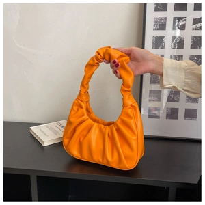 Detail of an orange ruched cloud bag showing soft leather texture and stylish knot strap