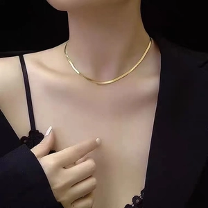Polished gold herringbone snake chain necklace for women on minimalist black background