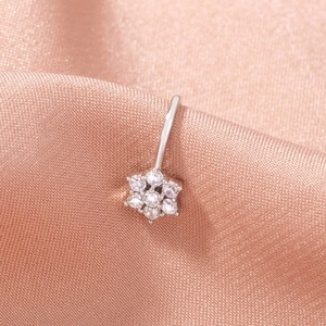 Macro shot of silver flower nose ring with inlaid stones on soft peach silk fabric