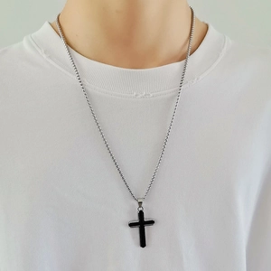 Collier à billes argentées avec pendentif croix noir et argent porté par un mannequin