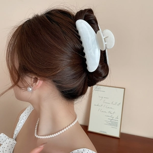 Détail d'une pince à cheveux en acrylique marbré sur une coiffure relevée élégante