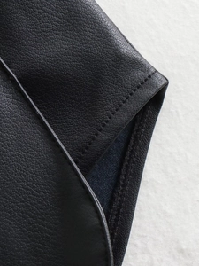 Detailed macro view of black leather vest featuring fine stitching and premium texture