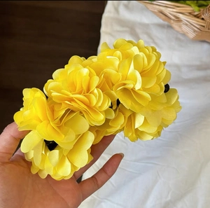 Close-up of a large bright yellow artificial flower hair clip with layered petals detail