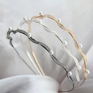Dettaglio di cerchietti ondulati con perle bianche eleganti in oro, argento e grigio