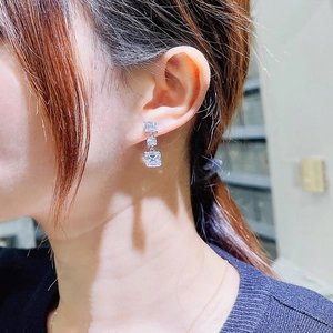 Gros plan de boucles d'oreilles argentées avec trois pierres en zircone cubique sur l'oreille