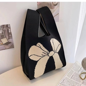 Minimalist black knitted tote bag featuring a prominent white bow pattern design