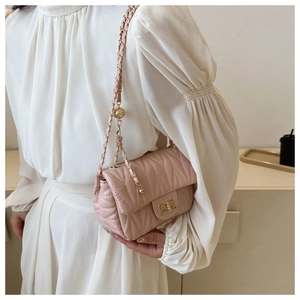 Detail of pink quilted leather crossbody bag with metal chain strap and turn-lock