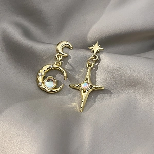 Detail of moon and star gold earrings with iridescent moonstone on gray silk