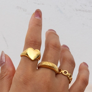 Close-up of gold-plated stainless steel stackable rings with heart and chain designs