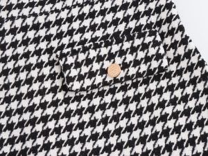 Détail de la texture du tissu en tweed pied-de-poule avec bouton en métal doré sur poche