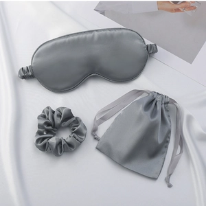Three-piece gray silk sleep set featuring a soft eye mask, scrunchie, and drawstring bag