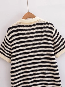 Dettaglio della polo in maglia a righe bianche e nere con trama a maglia traforata fine