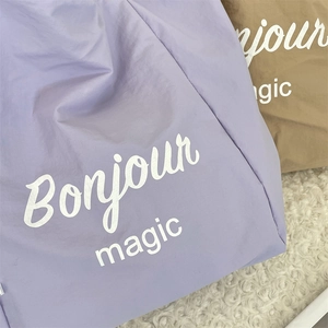 Close-up of lavender and khaki tote bags with 'Bonjour' print on soft faux fur surface
