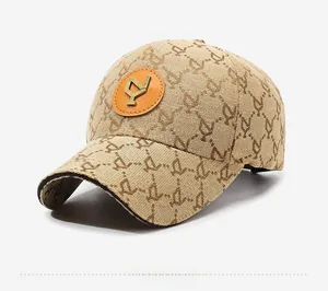 Detail of light khaki baseball cap featuring vintage pattern and metallic logo on leather patch