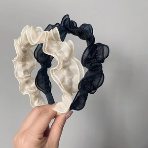Detail of pleated sheer mesh headbands in cream and black with wavy ruffled texture