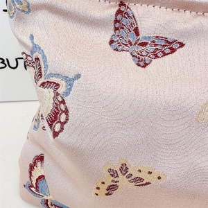 Close-up of intricate butterfly jacquard embroidery on soft pink textile shoulder bag