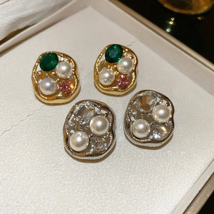 Macro detail of irregular pearl earrings with rhinestones in gold and silver finishes