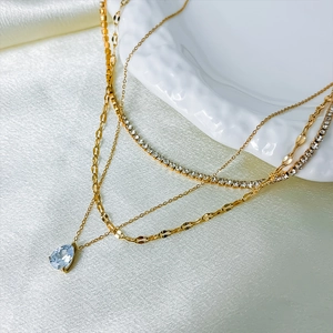 Macro view of layered gold necklace featuring a blue pear-shaped zircon pendant