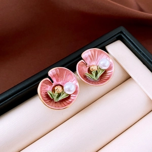 Detailed macro view of pink enamel flower earrings with white pearl center and green leaves