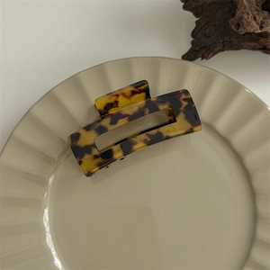 Detailed view of a dark leopard print acetate hair claw clip on a minimalist ceramic tray