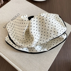 Detail of satin polka dot scrunchie with black piping edges on a vintage book