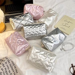 Flat lay of quilted heart and butterfly cosmetic bags in pink and silver finishes