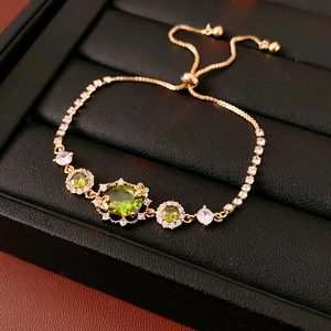 Détail macro du bracelet doré avec pierres vertes ovales et fermoir coulissant réglable
