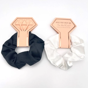 Detail of black and white silk scrunchies on rose gold diamond ring card packaging