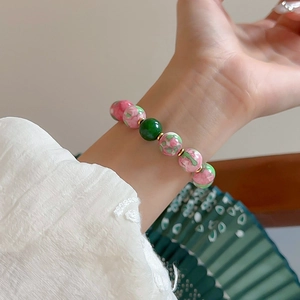 Close-up of elegant gold-plated bracelet with red and green gradient glass beads