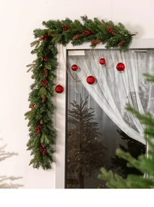 Lush PE mixed Christmas garland with red berries and pine cones on a window frame