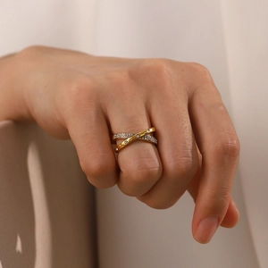 Nahaufnahme des 18K vergoldeten Kreuzrings mit eingelegten Diamanten an der Hand