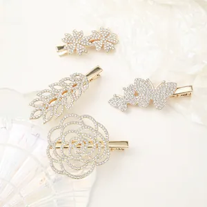 Detailed macro view of four gold-plated rhinestone hair clips in floral and leaf shapes