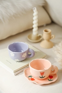 Close-up of handmade tulip pattern ceramic coffee mug and saucer in soft pink finish