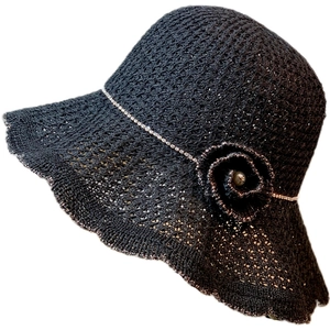 Women's black knit sun hat with floral detail and gold wave edge on white background