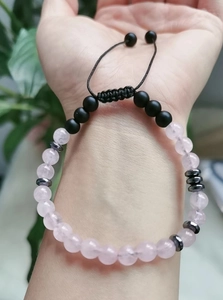 Detail of a pink rose quartz and black matte beaded bracelet on a braided cord