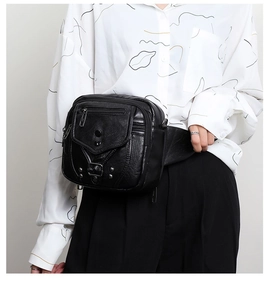 Détail du sac bandoulière en similicuir noir avec fermetures éclair et boucle sur modèle