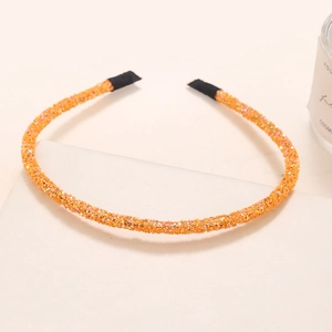 Detail of thin orange headband with shimmering glitter finish on a white display