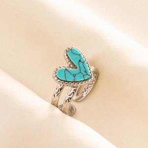 Detail of turquoise heart ring with double-layered engraved silver band on silk background