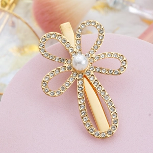 Golden flower hair clip with sparkling rhinestones and white pearl on a pink display stand