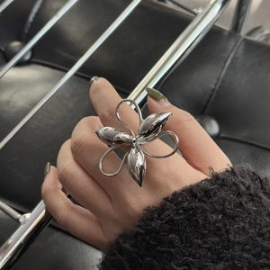 Detailed view of an oversized silver flower ring with artistic petals on a fashion model